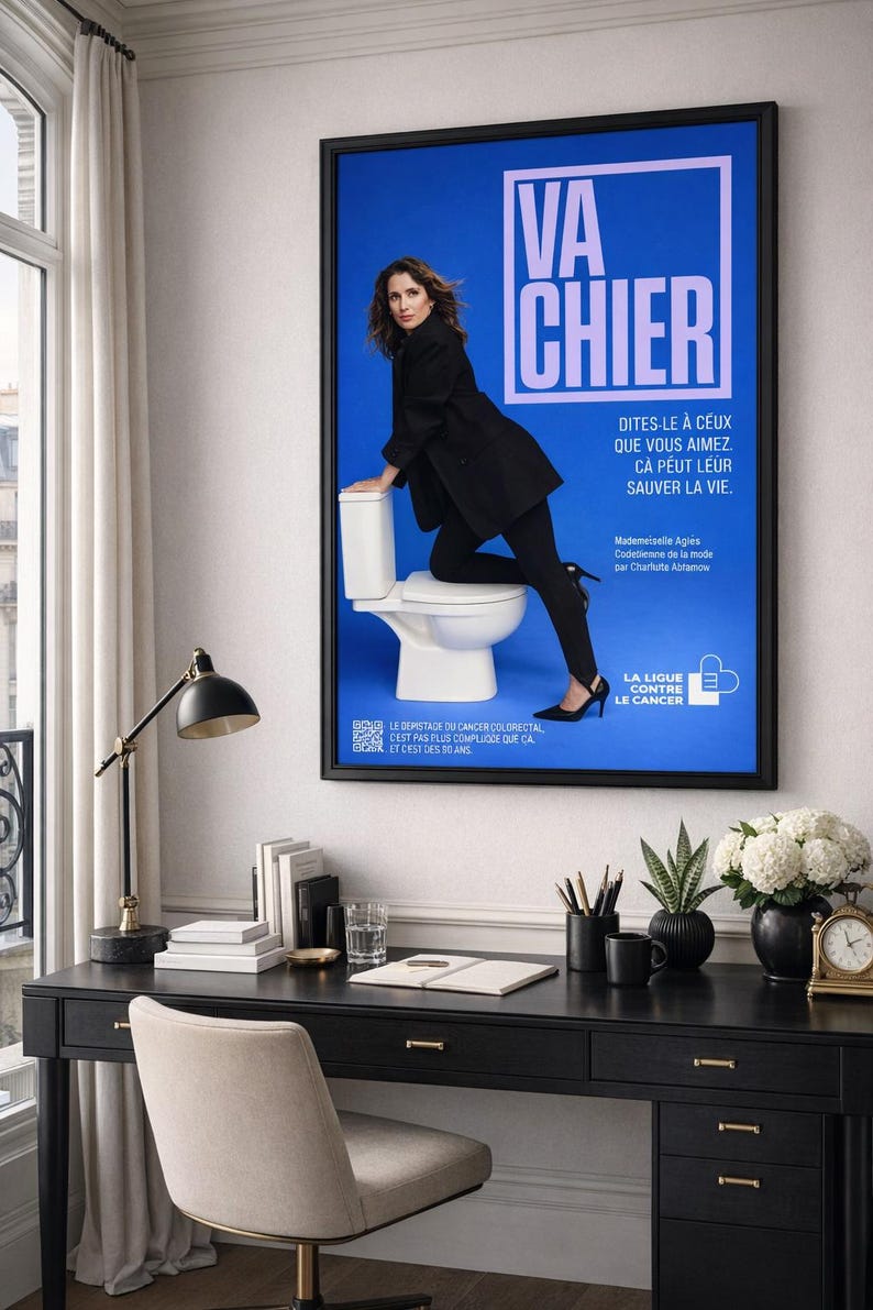 Puede incluir: Un p&oacute;ster enmarcado con el texto "VA CHIER" en blanco sobre fondo azul. Tambi&eacute;n incluye texto en franc&eacute;s y la imagen de una mujer vestida de negro. El p&oacute;ster est&aacute; sobre un escritorio negro.