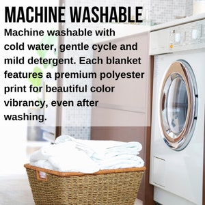 May include: A white washing machine with a silver door and a basket of white towels in a wicker basket. The text "MACHINE WASHABLE" is displayed above the image. The text below the image reads "Machine washable with cold water, gentle cycle and mild detergent. Each blanket features a premium polyester print for beautiful color vibrancy, even after washing."