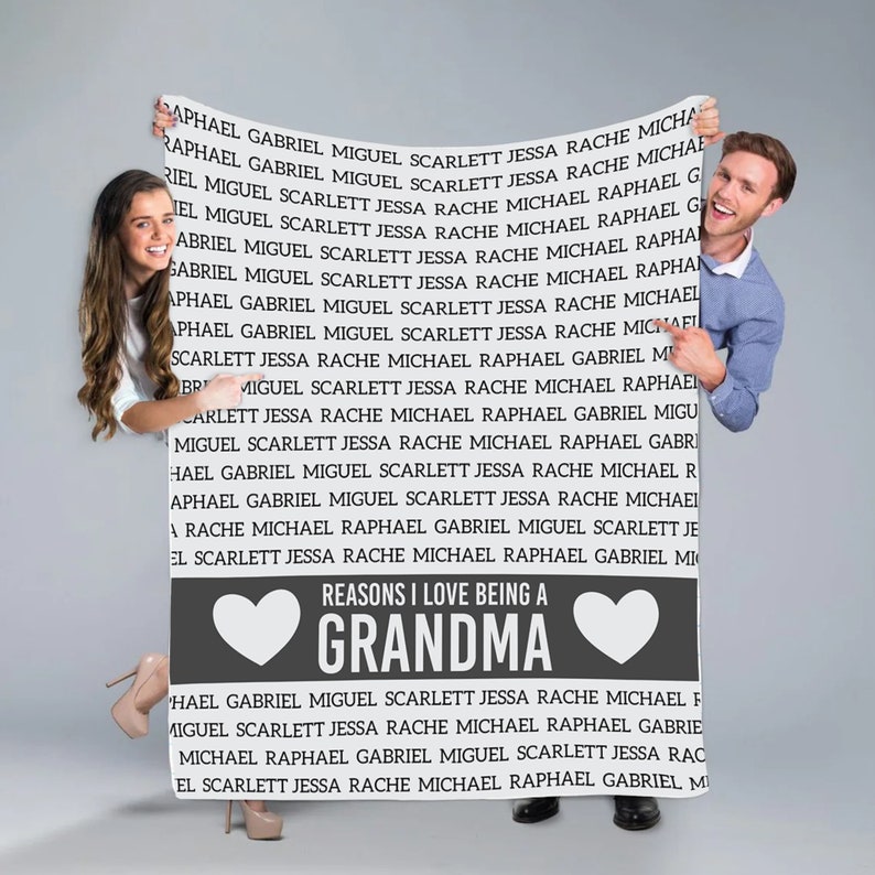 May include: A gray and white sign with the text "Reasons I love being a Grandma" and a heart on each side of the text. The sign is held up by a man and a woman.