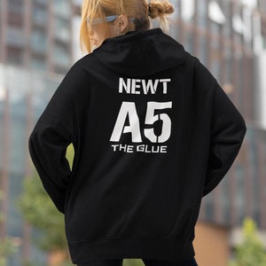 May include: Black hooded sweatshirt with white text on the back that reads "NEWT A5 THE GLUE".