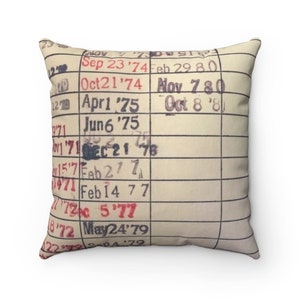 May include: A vintage-style cushion featuring a close-up of a library card with dates stamped in red ink. The dates range from September 1974 to May 1979.