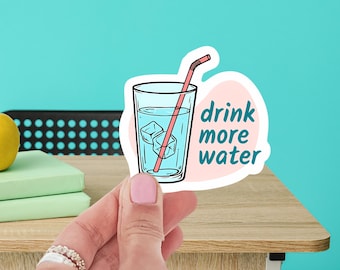 May include: A pink and white sticker with a cartoon illustration of a glass of water with ice cubes and a pink straw. The text "drink more water" is written in blue.