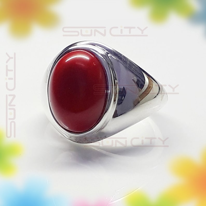 May include: A silver ring with a large, oval-shaped red gemstone.