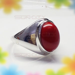 May include: A silver ring with a large, oval-shaped, red gemstone.