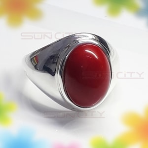 May include: A silver ring with a large, oval-shaped, red gemstone.
