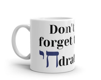 May include: White ceramic mug with black text that reads "Don't forget to" and a blue Hebrew letter "Heh" followed by the word "hydrate".