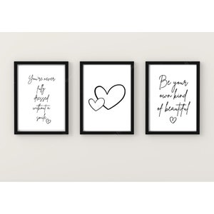 Op de afbeelding: Drie zwarte ingelijste prints met witte achtergronden en zwarte tekst. De linker print zegt "You're never fully dressed without a smile." De middelste print heeft twee zwarte harten. De rechter print zegt "Be your own kind of beautiful."