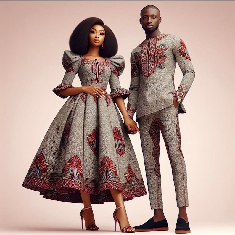 May include: A couple wearing matching gray and red patterned outfits. The woman is wearing a dress with a full skirt and the man is wearing a long-sleeved shirt and pants.