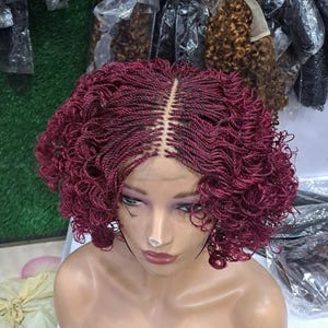 May include: A burgundy colored wig with a curly, braided style. The wig is made with synthetic hair and is designed for a natural look.