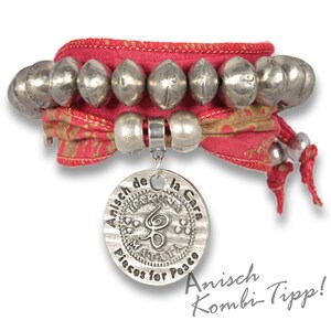 May include: A red and gold fabric bracelet with silver beads and a silver charm that says "Anisch de la Cara Pisces for Peace".