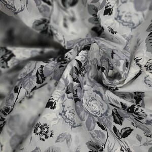 Puede incluir: Tela blanca con estampado floral negro y gris. La tela es transparente y tiene una textura delicada.