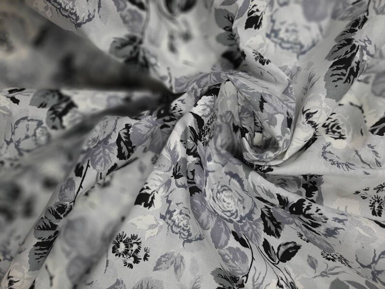 Puede incluir: Tela blanca con estampado floral negro y gris. La tela es transparente y tiene una textura delicada.