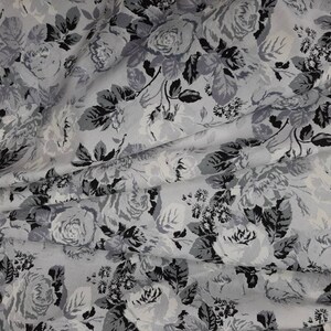 Puede incluir: Una tela blanca con estampado floral negro y gris. La tela presenta un patr&oacute;n repetitivo de rosas y hojas.