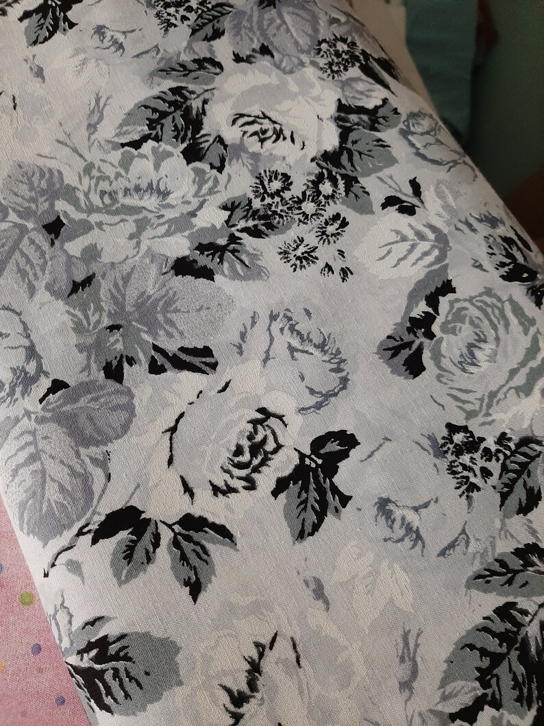 Puede incluir: Una tela blanca con un patr&oacute;n floral con rosas y hojas negras y grises.