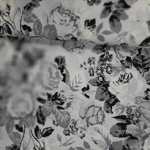 Puede incluir: Una tela blanca con un patr&oacute;n floral negro y gris. La tela tiene un brillo sutil y una textura suave.