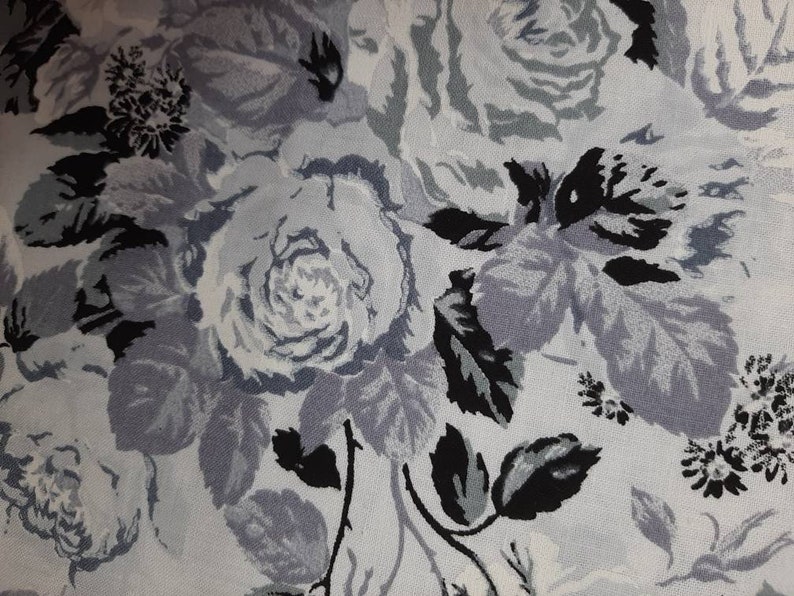 Puede incluir: Una tela blanca con un patr&oacute;n floral negro y gris. El patr&oacute;n presenta rosas y hojas.