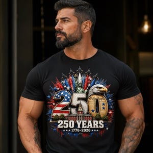 May include: A black short-sleeved t-shirt featuring a graphic design with the number 250, a bald eagle, the Statue of Liberty, and Independence Hall. The text reads 250 YEARS 1776-2026, with red, white, and blue patriotic star and firework accents.