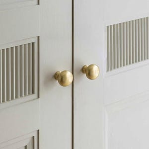 May include: A white ceramic mug with a black handle and the text "But First, Coffee" in a black, handwritten-style font. The mug is on a white surface.