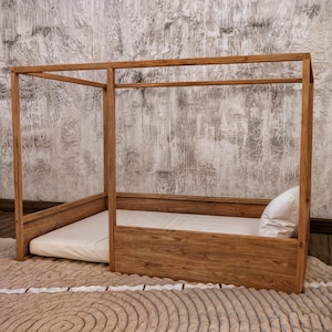 May include: A wooden canopy bed frame with a white mattress and pillow. The bed frame is made of natural wood and has a simple, modern design.
