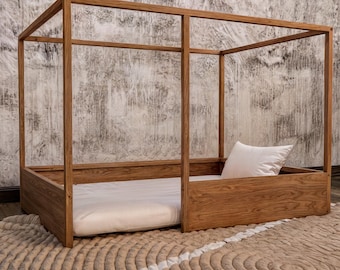 May include: A wooden canopy bed frame with a white mattress and a white pillow. The bed frame is made of natural wood and has a simple, modern design.