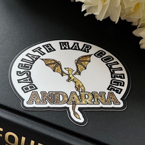 May include: A white sticker with a black and gold dragon design. The sticker says "Brisingr War College Andarna".