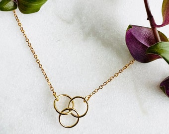 May include: A gold chain necklace with a pendant featuring three interlocking circles.