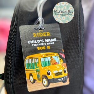 Pu&ograve; includere: Uno zaino nero con un'etichetta di autobus scolastico gialla attaccata. L'etichetta ha il testo "BUS RIDER", "CHILD'S NAME", "TEACHER'S NAME" e "BUS #". L'etichetta presenta anche un autobus scolastico di cartoni animati con un viso sorridente.