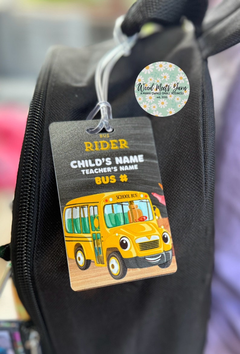 Pu&ograve; includere: Uno zaino nero con un'etichetta di autobus scolastico gialla attaccata. L'etichetta ha il testo "BUS RIDER", "CHILD'S NAME", "TEACHER'S NAME" e "BUS #". L'etichetta presenta anche un autobus scolastico di cartoni animati con un viso sorridente.