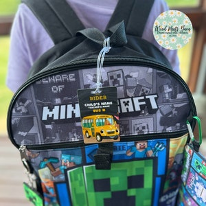 Pu&ograve; includere: Uno zaino nero Minecraft con una faccia di Creeper verde sul davanti. Lo zaino ha una borsa pranzo abbinata con un design Minecraft. Un'etichetta di passeggero dell'autobus &egrave; attaccata allo zaino con il testo "Bus Rider, Child's Name, Teacher's Name, Bus #".