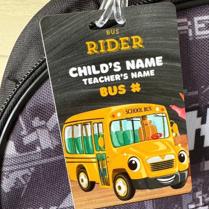 Pu&ograve; includere: Un'etichetta di bus scolastico nera e gialla con il testo "BUS RIDER" e "CHILD'S NAME" e "TEACHER'S NAME" e "BUS #". Un autobus scolastico giallo dei cartoni animati con un viso sorridente &egrave; sull'etichetta.