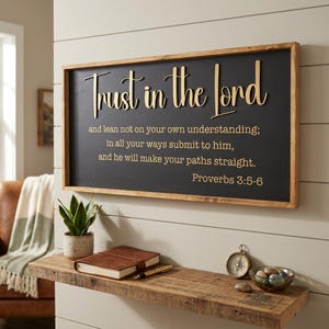 May include: A rectangular wall sign with a natural wood frame and a black background featuring the gold text Trust in the Lord and lean not on your own understanding; in all your ways submit to him, and he will make your paths straight. Proverbs 3:5-6.