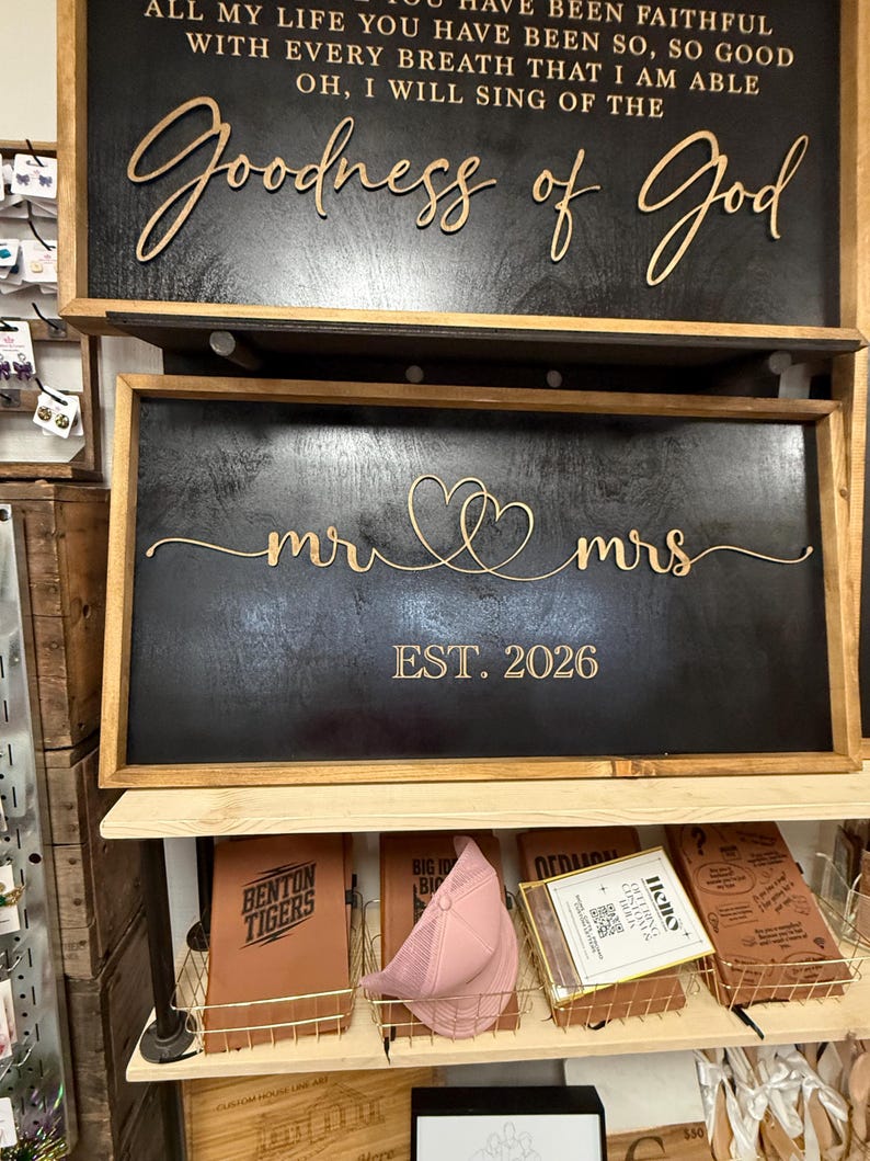May include: Two rectangular wooden signs with black backgrounds and light wood frames. The top sign features the text "All my life you have been faithful with every breath that I am able oh, I will sing of the Goodness of God". The bottom sign displays "mr" and "mrs" with two connected hearts and "EST. 2026".