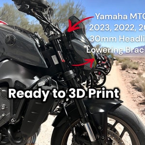 May include: A gray Yamaha MT09 motorcycle with a 30mm headlight lowering bracket. The bracket is ready to be 3D printed. The motorcycle is parked in a desert environment.