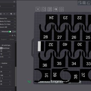 Könnte beinhalten: Ein Screenshot einer 3D-Druck-Softwareoberfläche, die ein Design für einen Satz von 40 schwarzen Kunststoffteilen zeigt. Die Teile sind von 22 bis 39 nummeriert und in einem Raster angeordnet. Die Softwareoberfläche enthält Einstellungen für Druckqualität, Glätten und Wandgenerierung.