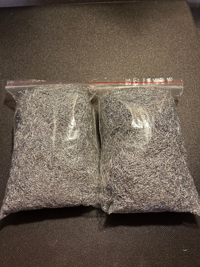 May include: Two clear plastic bags filled with silver metallic shredded packing material.