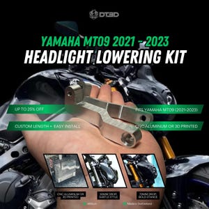 May include: A silver headlight lowering kit for Yamaha MT09 motorcycles, model years 2021-2023. The kit is made of CNC aluminum or 3D printed material. The image includes text that says "Custom Length + Easy Install".