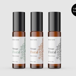Op de afbeelding: Drie amberkleurige glazen rollerflessen met zwarte dopjes en witte etiketten. De etiketten hebben een bloemmotief en de tekst "Vintage Floral Essential Oil Blend 10 ml / .33 fl oz".