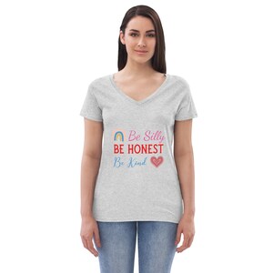 Op de afbeelding: Een grijs V-hals T-shirt met een regenboog en hart motief. De tekst op het shirt luidt "Be Silly, Be Honest, Be Kind".