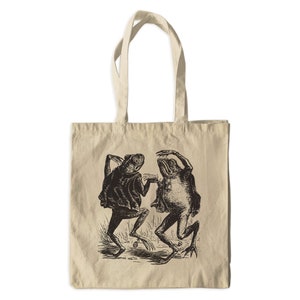 May include: A beige tote bag with a black and white illustration of two frogs dancing. The frogs are wearing a suit and a dress.