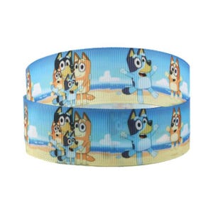 May include: Blue ribbon with a repeating pattern of cartoon dogs on a beach. The ribbon design features animated dogs in various poses against a backdrop of a sandy beach, ocean, and sky.