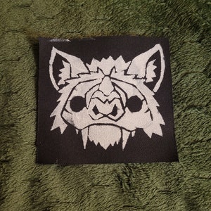 May include: White embroidered bat face on a black fabric patch.