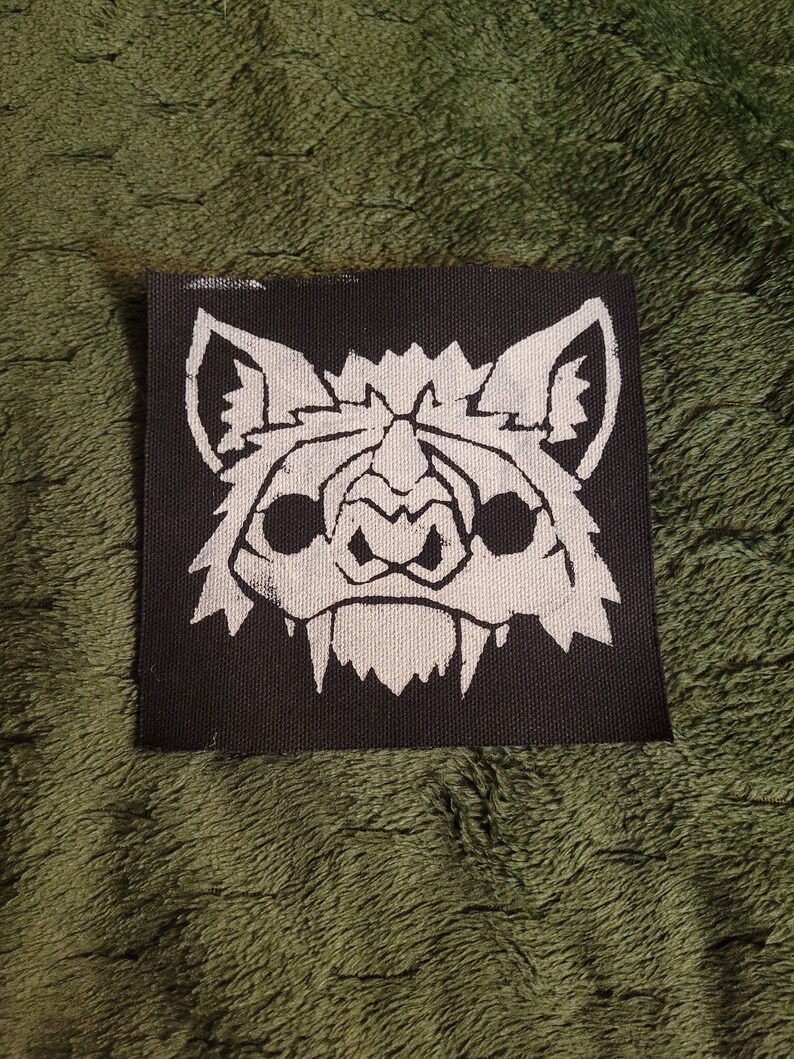 May include: White embroidered bat face on a black fabric patch.