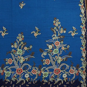 Może przedstawiać: Niebieski materiał z kwiatowym wzorem. Kwiaty są w odcieniach czerwonego, różowego, białego, zielonego i żółtego. Materiał ma ciemnoniebieską obwódkę z mniejszym kwiatowym wzorem.