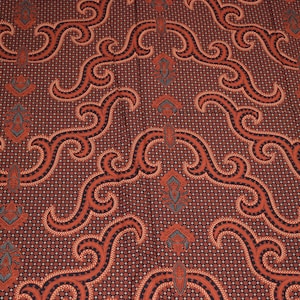 Könnte beinhalten: Roter und schwarzer Stoff mit einem sich wiederholenden Muster aus wirbelnden Linien und kleinen floralen Motiven.