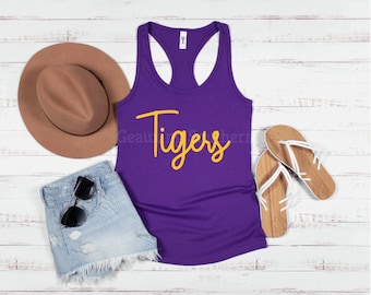 May include: Purple tank top with the word "Tigers" written in yellow cursive lettering.
