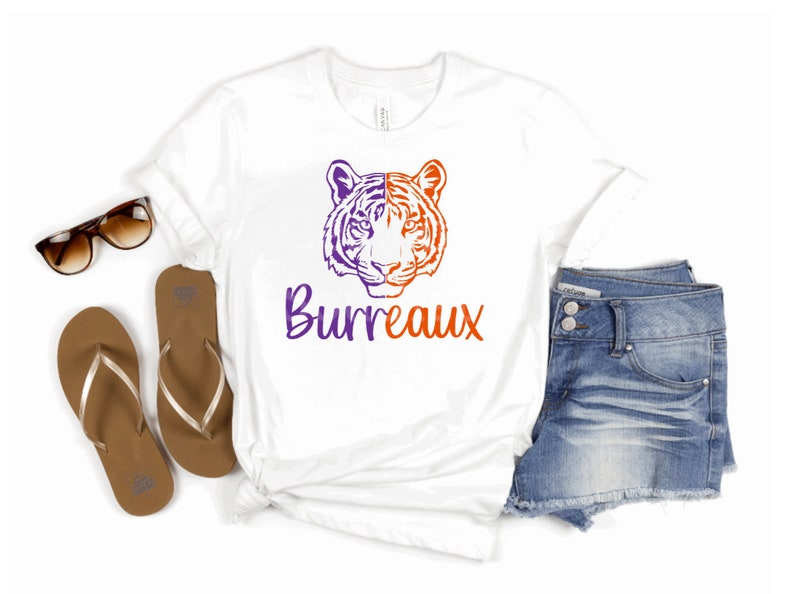 May include: White t-shirt with a purple and orange tiger head graphic and the text "Burreaux" in purple.