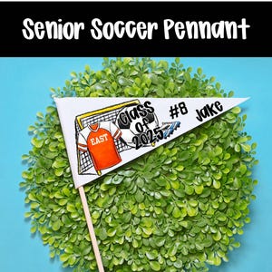 Op de afbeelding: Een witte vlag met zwarte tekst en een voetbalafbeelding. De tekst luidt "Class of 2025" en "#8 Jake".