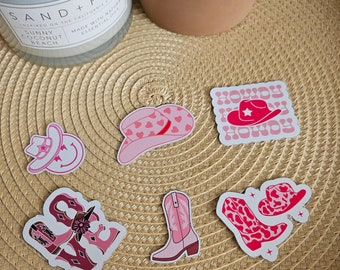 Könnte beinhalten: Sechs rosafarbene und weiße Cowboy-Sticker mit verschiedenen Designs, darunter ein Cowboyhut, Stiefel und die Worte "Howdy Howdy".