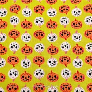 May include: A bright yellow fabric featuring a repeating pattern of stylized jack-o'-lanterns in alternating orange and white colors. Each pumpkin has a simple black face with triangular eyes, a small nose, and a jagged mouth. Text reads Little Fawn Fabric.