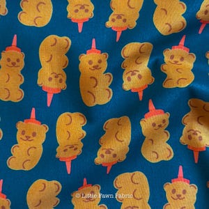 May include: Fabric with a repeating pattern of yellow teddy bears with orange hats and red cones on a teal background. The bears have smiling faces and are in various orientations. The text "Little Fawn Fabric" is in the bottom right corner.